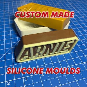 May include: Custom made silicone molds for creating a chocolate bar with the word "ARWE" embossed on the top. The molds are brown, white, and yellow.