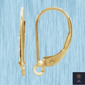 May include: Close-up of two gold-colored leverback earring findings. The findings are made of shiny metal and have a curved design with a small loop at the bottom. The background is a light blue color.