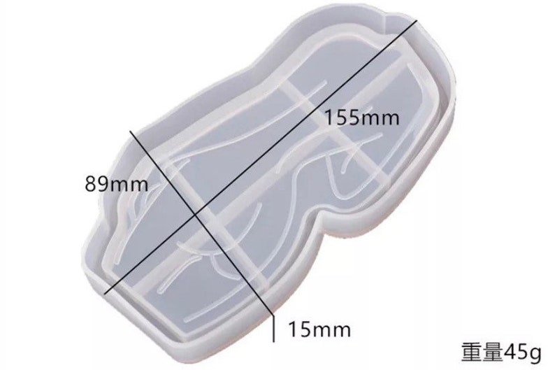 May include: A clear, rectangular silicone mold with rounded edges, designed for crafting. The mold measures 155mm long, 89mm wide, and 15mm deep. The weight is 45g. The mold has a unique shape with internal dividers.
