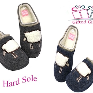 May include: Two pairs of gray wool slippers with a sheep design. The slippers have a hard sole and a fluffy white sheep embroidered on the front. The slippers are labeled "Gifted Gifts" and "Hard Sole".
