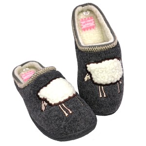 May include: A pair of gray wool slippers with a sheep design. The slippers have a white sheep with brown eyes and legs embroidered on the front. The slippers have a beige trim around the top and a pink label on the inside.