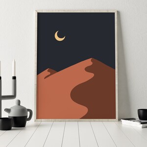 May include: Abstract art print featuring a crescent moon in a dark blue sky above a single orange sand dune.