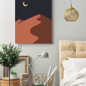 May include: A digital art print featuring a minimalist desert landscape with a crescent moon in the night sky. The print has a dark blue background and the sand dunes are a warm orange color.