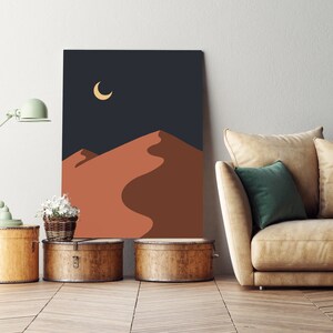 May include: A digital art print of a desert landscape with a crescent moon in the night sky. The print features a minimalist design with a dark blue background and a reddish-brown sand dune.