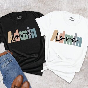 May include: Two t-shirts with the text "Admin Love" in rainbow colors. The shirts are black and white.