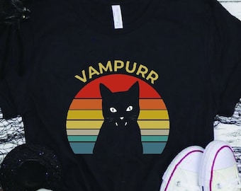 May include: Black t-shirt with a retro sunset graphic and a black cat silhouette. The text "Vampurr" is printed above the graphic.