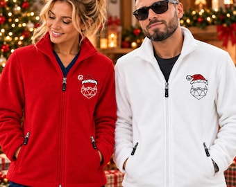 May include: A red fleece jacket and a white fleece jacket, each featuring a full-length front zip, a high collar, and two side pockets. On the left chest of each jacket is a geometric line art graphic of a Santa Claus face and hat.