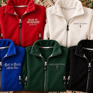 May include: Five fleece zip-up jackets in red, white, blue, green, and black. Each jacket features a high collar, silver zippers, and religious text: Made to Worship, Jesus is King, God is Good All the Time, Faith Over Fear, and Thankful.