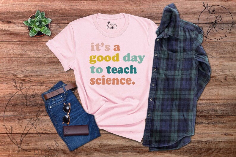 Op de afbeelding: Roze T-shirt met de tekst "it's a good day to teach science." in kleurrijk retro lettertype.