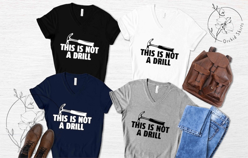 May include: Four V-neck t-shirts in black, navy blue, white, and heather gray with a black and white graphic of a hammer and the text "This is not a drill".