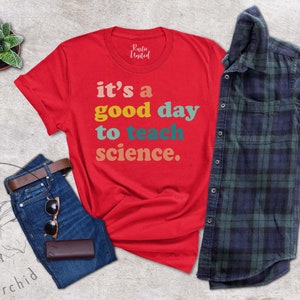 Op de afbeelding: Rood T-shirt met de tekst "it's a good day to teach science." in kleurrijk retro-lettertype.
