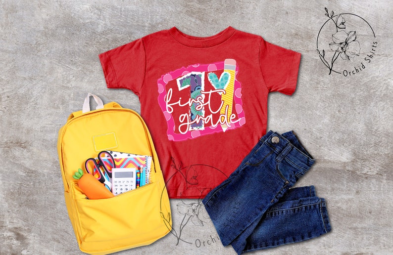 May include: Red t-shirt with a colourful graphic that says "1st grade" with a pencil and heart. A yellow backpack with school supplies, blue jeans, and a white flower.