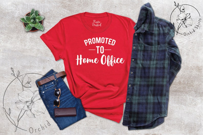 May include: A red t-shirt with the text "PROMOTED - TO - Home Office" in white, alongside blue jeans, a brown belt, sunglasses, and a wallet. A green and navy plaid shirt is also included.