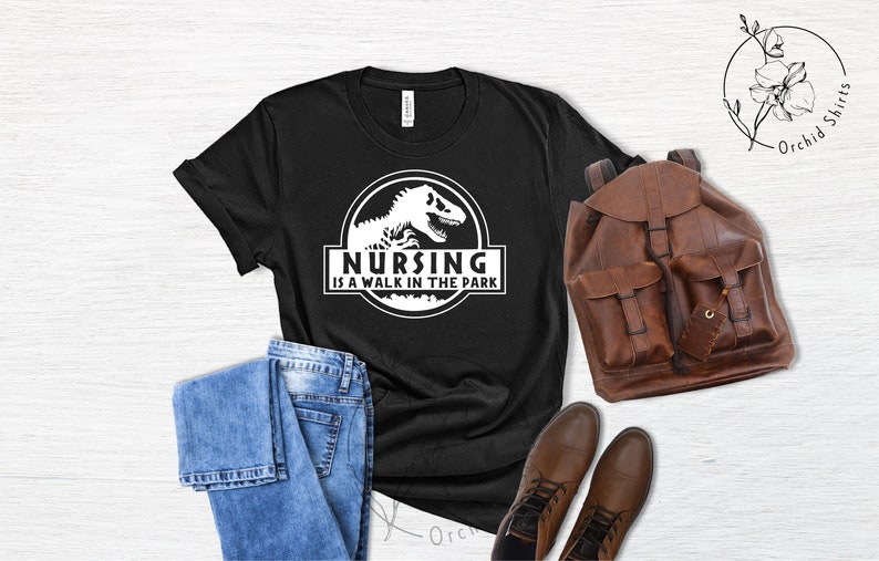 May include: Black t-shirt with a white graphic of a dinosaur and the text "Nursing is a walk in the park".