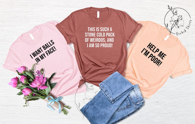 May include: Three graphic t-shirts in pink, rust, and peach, each with bold black text. The pink shirt reads "I WANT BALLS IN MY FACE!", the rust shirt says "THIS IS SUCH A STONE COLD PACK OF WEIRDOS, AND I AM SO PROUD!", and the peach shirt says "HELP ME I'M POOR!".