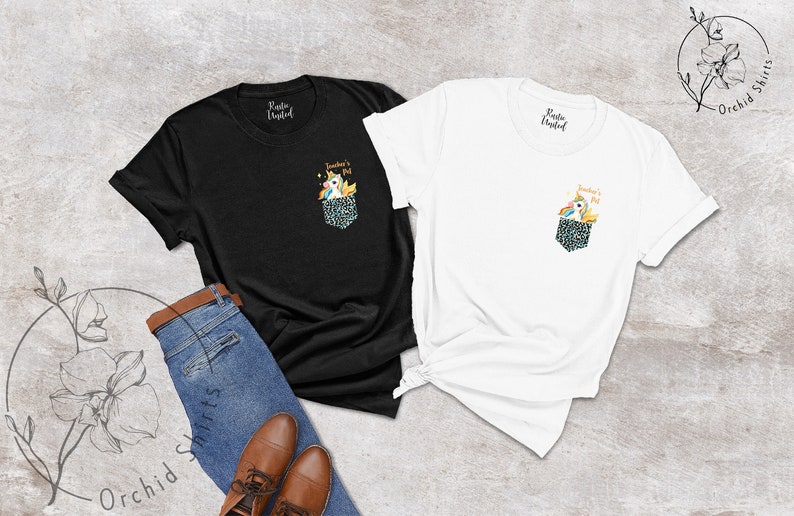 May include: Black and white t-shirts with a pocket design featuring a unicorn. The pocket has a leopard print pattern. The text on the pocket says "Teacher's Pet". A pair of blue jeans and brown shoes are also in the image.