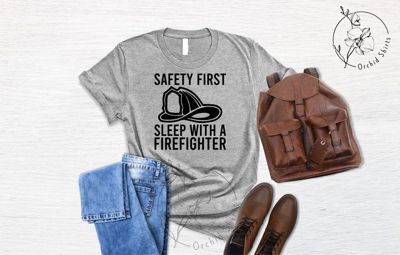 May include: A gray t-shirt with the text "Safety First Sleep with a Firefighter" and a black illustration of a firefighter's helmet.