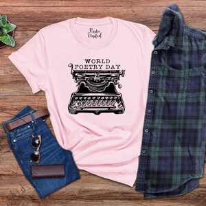 May include: A pink t-shirt featuring the text "WORLD POETRY DAY" and a vintage typewriter graphic.