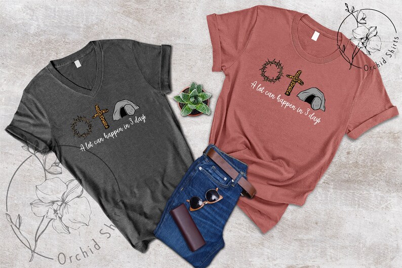 K&ouml;nnte beinhalten: Zwei T-Shirts mit einem christlichen Ostern-Motiv. Das graue Shirt hat eine Dornenkrone, ein Kreuz und ein Grab mit dem Text "In 3 Tagen kann viel passieren". Das rosa Shirt hat das gleiche Design mit dem Text "In 3 Tagen kann viel passieren".