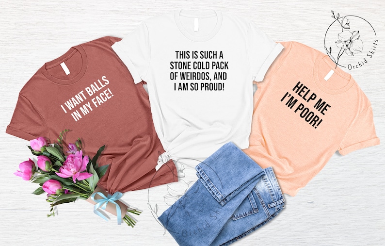 May include: Three t-shirts with humorous phrases in black text. One is brick red and says "I WANT BALLS IN MY FACE!". The second is white and says "THIS IS SUCH A STONE COLD PACK OF WEIRDOS, AND I AM SO PROUD!". The third is peach and says "HELP ME I'M POOR!".