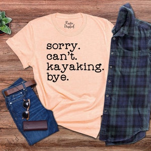 May include: A peach-colored t-shirt with the text "sorry. can't. kayaking. bye." printed in black.