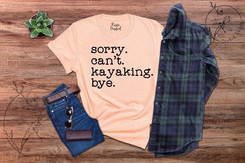 May include: A peach-colored t-shirt with the text "sorry. can't. kayaking. bye." printed in black.
