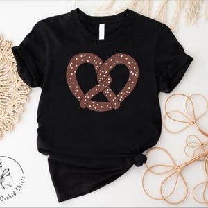 Pu&ograve; includere: Maglietta nera con un pretzel marrone con spruzzi bianchi.