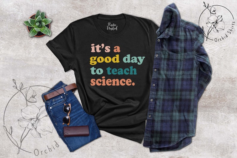 Op de afbeelding: Zwart T-shirt met de tekst "it's a good day to teach science." in regenboogkleuren.