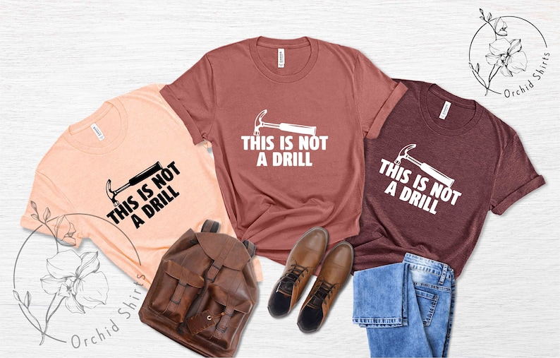 May include: Three t-shirts with the text "This is not a drill" and a hammer graphic. The shirts are in peach, maroon, and heather gray.