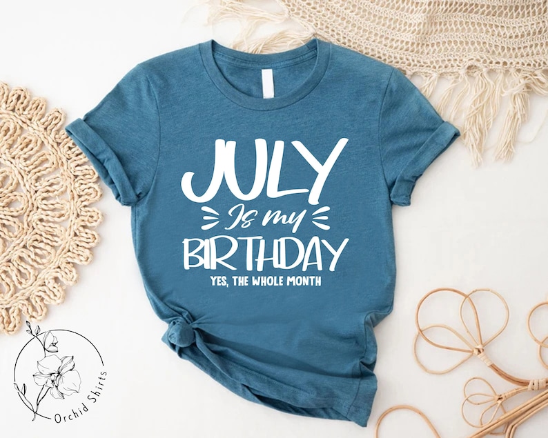 May include: A teal blue t-shirt with white text that reads "JULY is my BIRTHDAY YES, THE WHOLE MONTH".