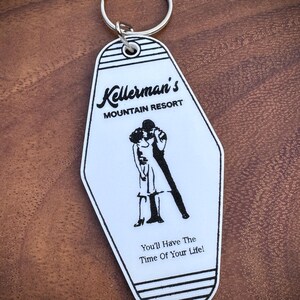 May include: White and black motel-style keychain with a silver ring. The keychain features the text "Kellerman's Mountain Resort" and a black silhouette of a couple dancing. The phrase "You'll Have The Time Of Your Life!" is also printed on the keychain.