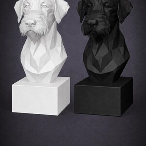 Peut inclure: Deux bustes de chien géométriques, un blanc et un noir, chacun monté sur une base carrée. Les bustes ont un design low-poly, avec des angles et des plans définis. Le fond est gris foncé.