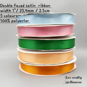 May include: Five spools of double-faced satin ribbon in light blue, pink, green, peach, and orange. The ribbon is 1 inch wide and made of 100% polyester.