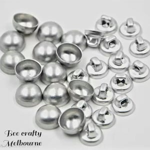 May include: A selection of silver metal buttons and half-sphere embellishments. Some buttons have a loop on the back. The text "Bee crafty Melbourne" is visible in the lower left corner.