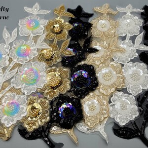 May include: Close-up of floral appliques in various colours, including white, gold, black, and iridescent. The appliques are embellished with sequins and beads, ideal for crafting and embellishments. The text "Bee crafty Melbourne" is visible.