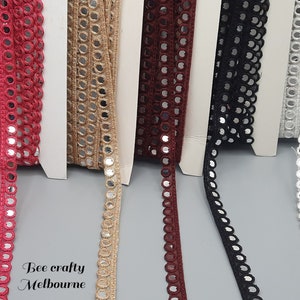 May include: Five spools of trim with mirrored circles. The trim is available in red, beige, burgundy, black, and white.