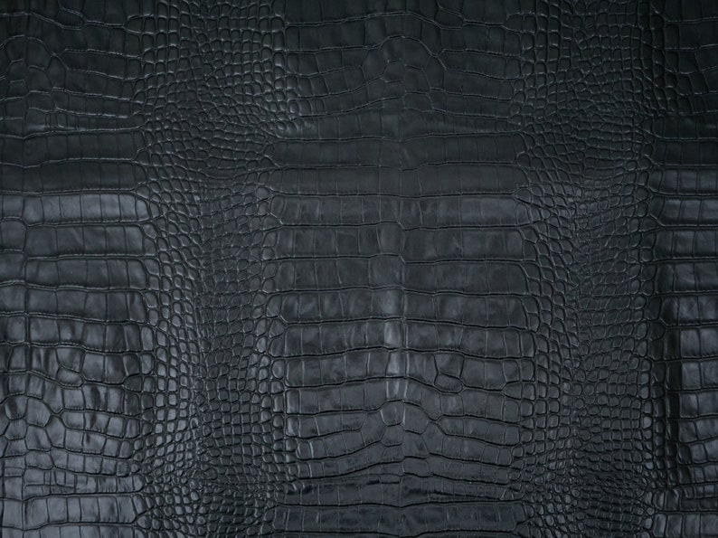 May include: Black crocodile embossed leather texture. The surface has a repeating pattern of scales.