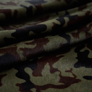 May include: Green, brown, and black camouflage fabric with a hairy texture.