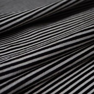 Puede incluir: Tela rayada en blanco y negro con una textura suave y peluda.