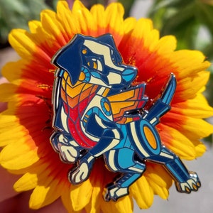May include: A colourful enamel pin of a cartoon dog with a blue, white and orange design. The dog is wearing a red and orange scarf and has a black and white face.