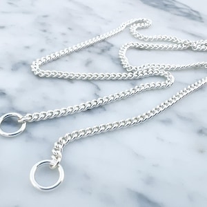 May include: A silver curb chain necklace with two silver rings at the ends.