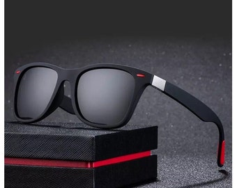 May include: Black sunglasses with a red accent on the frame and a black case.