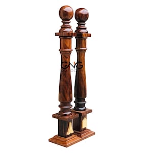 May include: Two wooden pillars with decorative finials and bases. The pillars are a rich brown colour with a wood grain pattern. The bases are square and have a gold accent.