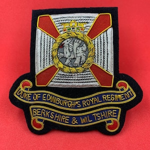 May include: A black embroidered patch with a red cross and a white and gold crest. The text "DUKE OF EDINBURGH'S ROYAL REGIMENT BERKSHIRE & WILTSHIRE" is on the patch.