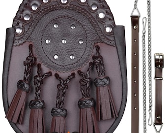 Puede incluir: Un sporran de cuero marrón con una cadena y una correa. El sporran tiene un diseño circular con tachuelas plateadas y borlas.