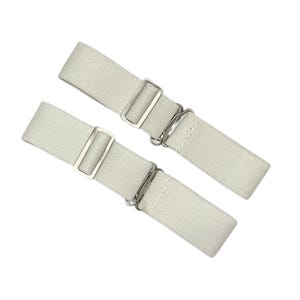 May include: Two white elastic sock garters with silver metal clasps. The garters are designed to keep socks from slipping down.