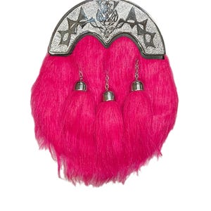 Op de afbeelding: Een roze kilt sporran met een zilveren distel- en kruisontwerp op de bovenklep. De sporran heeft drie kwastjes.