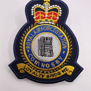 May include: A blue and gold embroidered patch with a crown, a building, and the text "Royal Air Force Station Comng Sby Loyalty Binds Me".