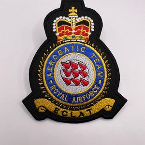 May include: A black embroidered patch featuring a gold crown, a blue circle with red arrows, and the text "Aerobatic Team - Royal Airforce - Eclat".