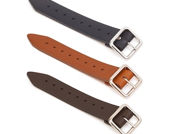 Puede incluir: Tres correas de cuero en negro, marrón y beige, cada una con una hebilla cuadrada plateada. Las correas tienen múltiples agujeros para ajuste y están dispuestas diagonalmente sobre un fondo blanco. Las hebillas son de color plata brillante.
